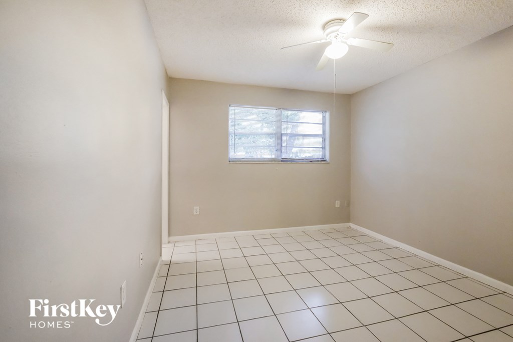 an empty living room with a white tiled floor and a window
