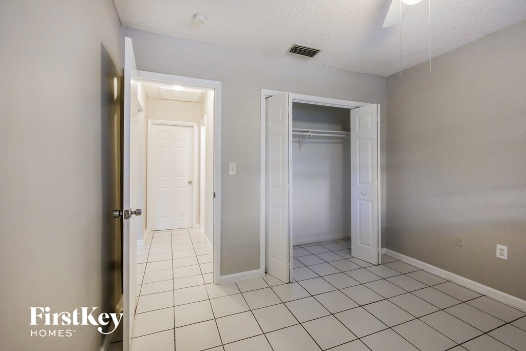 a tiled floor in a room with a closet and a door to a bathroom