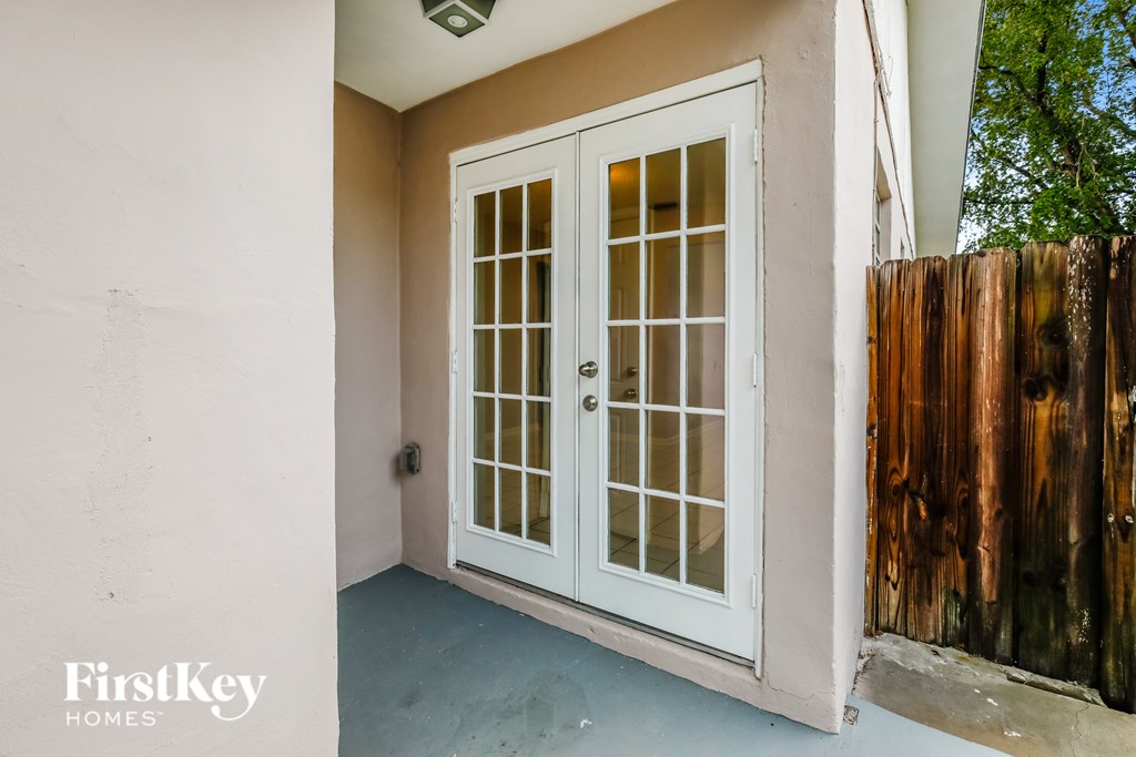 the front porch of a house with white doors and a wooden fence