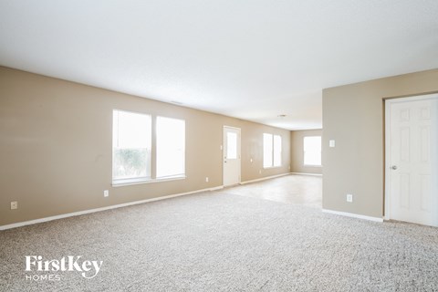 A spacious room with a carpeted floor and a door on the right side.