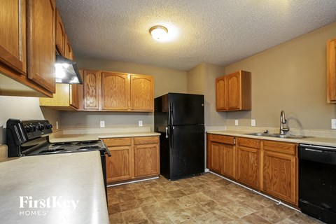 A kitchen with wooden cabinets and a black fridge.