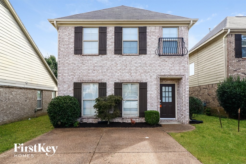 a white brick house with black shuttered windows and a driveway