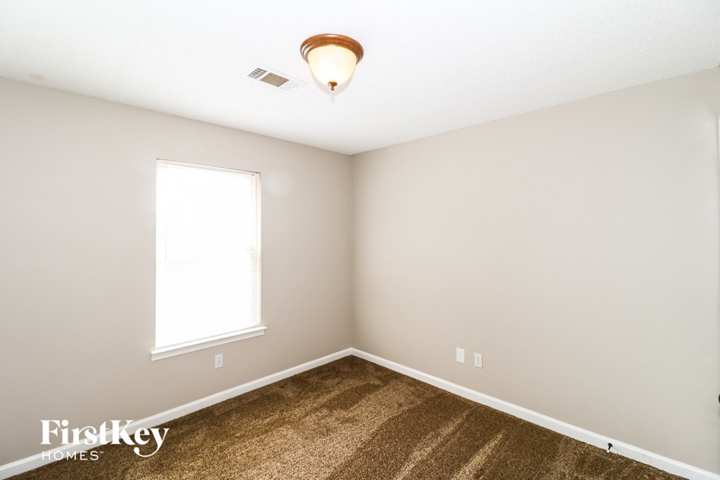 a bedroom with carpet and a window and a ceiling fan