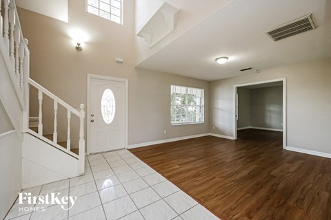 an empty living room with a staircase and a white door