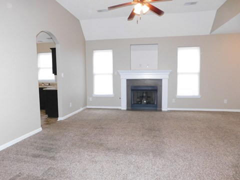 A living room with a fireplace and a ceiling fan.