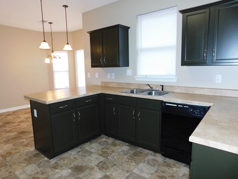 A kitchen with black cabinets and a stone floor.