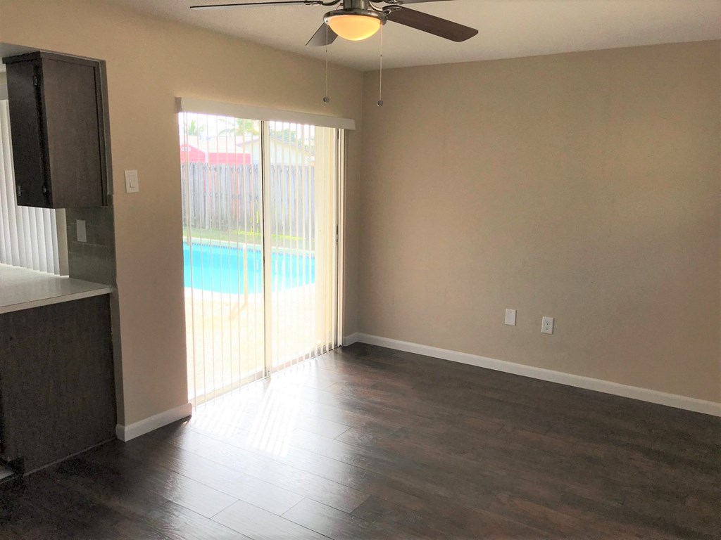 A room with a ceiling fan and sliding glass doors leading to a pool.