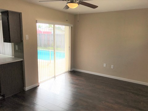 A room with a ceiling fan and sliding glass doors leading to a pool.