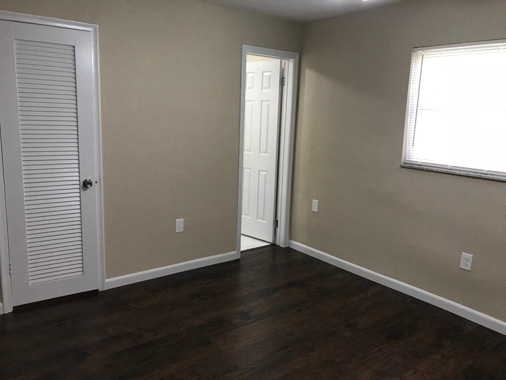 A room with a white door and a window with blinds.