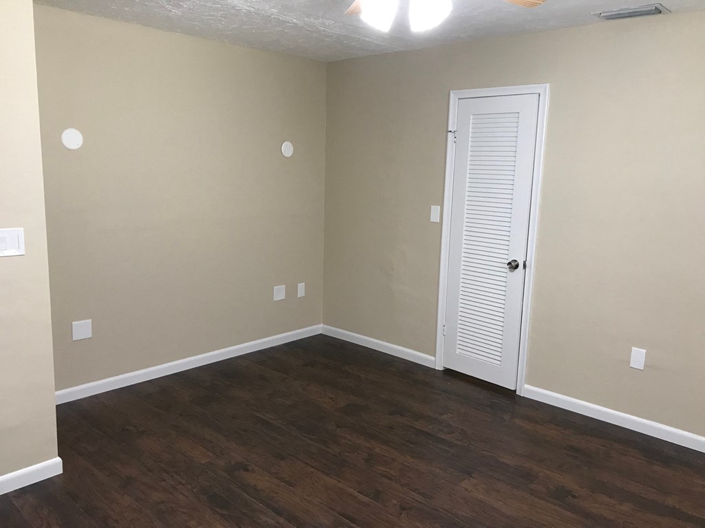A room with a white door and wooden flooring.