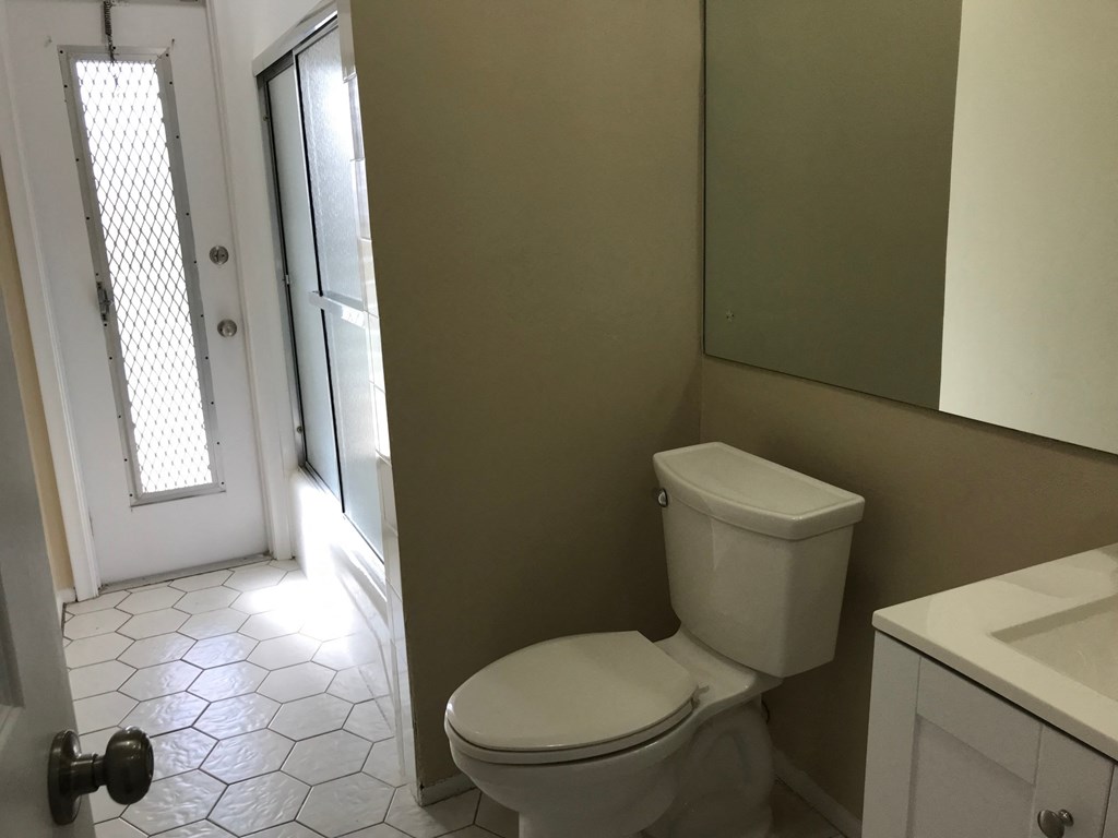 A white toilet in a bathroom with a white door and a white sink.
