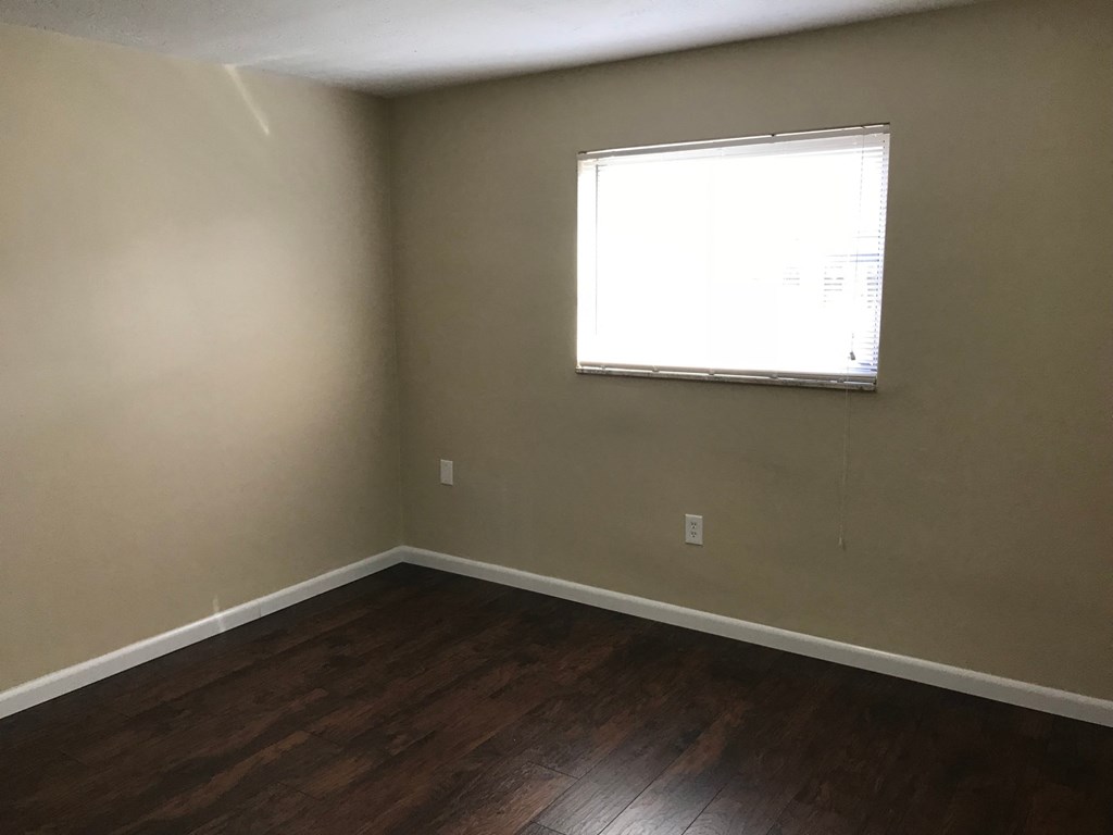 A room with a window and wooden flooring.
