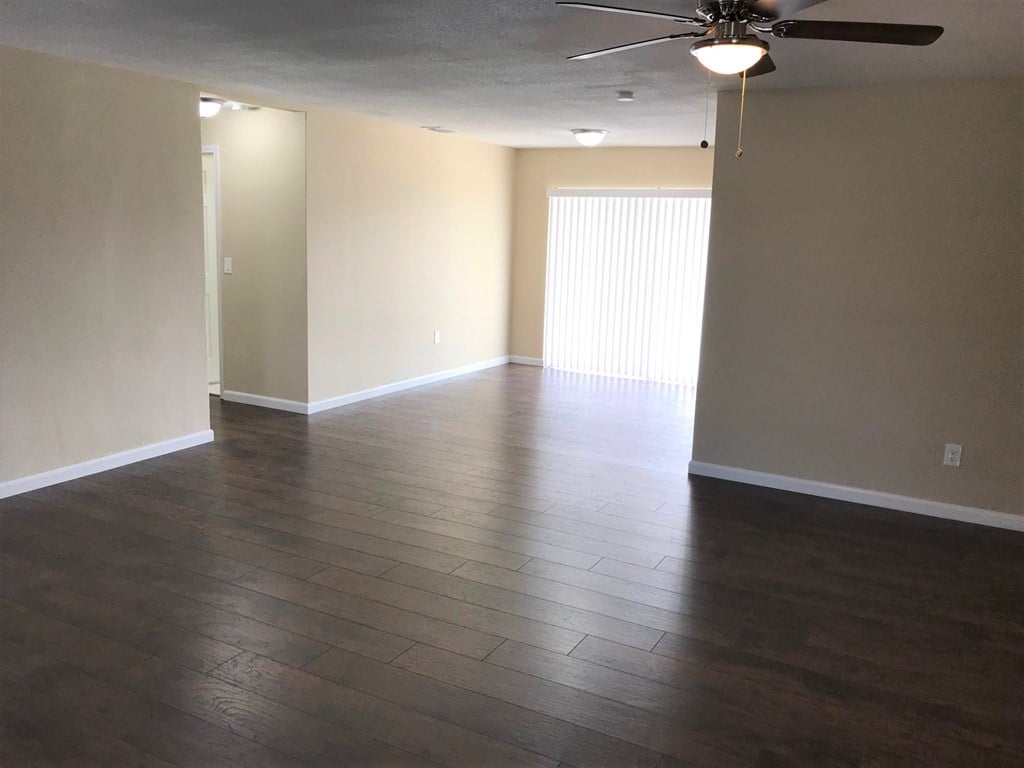 A room with a ceiling fan and wooden flooring.