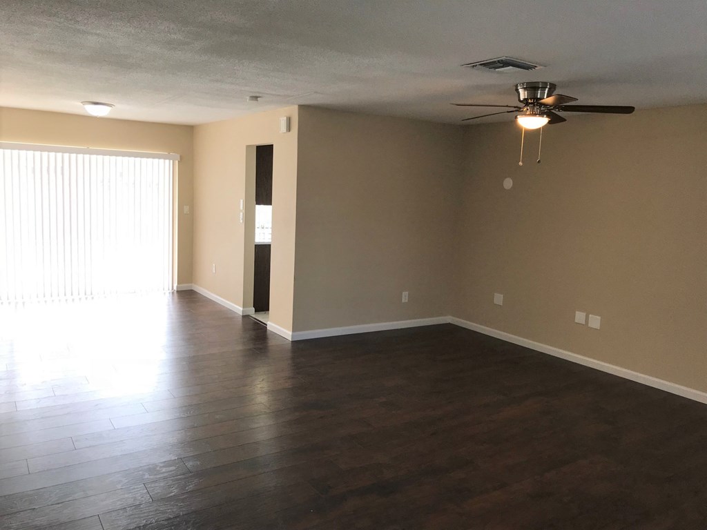 A room with a ceiling fan and a window with blinds.