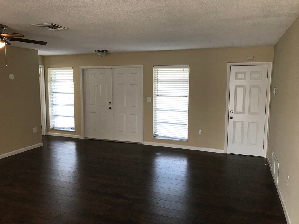 A room with a ceiling fan and three doors.