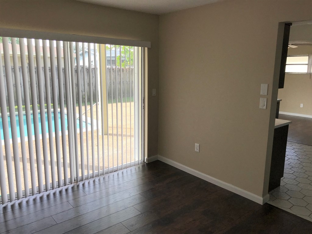 A room with a sliding glass door and wooden flooring.