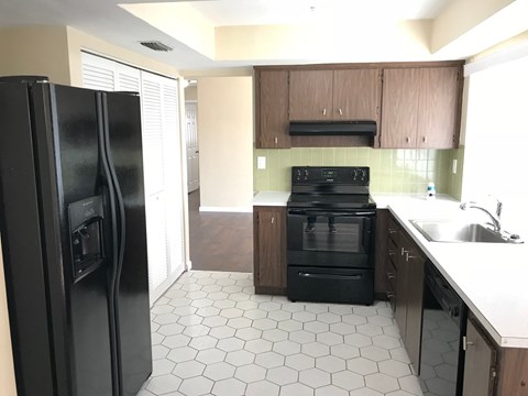 A black refrigerator is in a kitchen with black appliances.