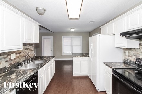A kitchen with white cabinets and a black stove top oven.