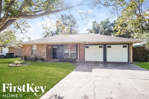 a brick house with two garage doors and a lawn