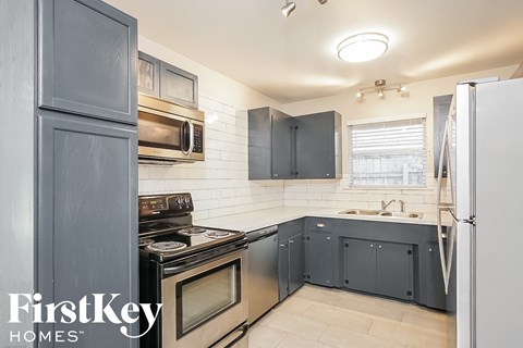 a kitchen with navy blue cabinets and white appliances and a sink