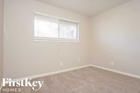 a bedroom with a window and a carpeted floor