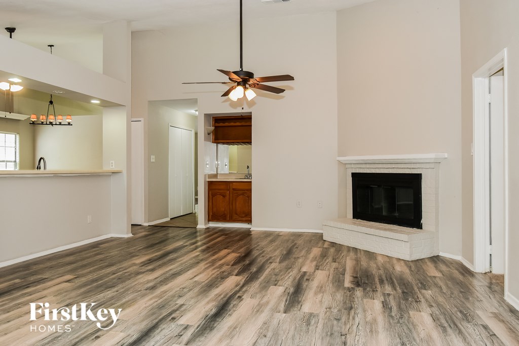 A spacious living room with a fireplace and wood flooring.