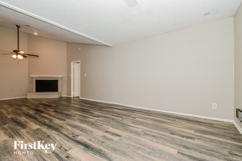 A spacious room with a fireplace and wood flooring.