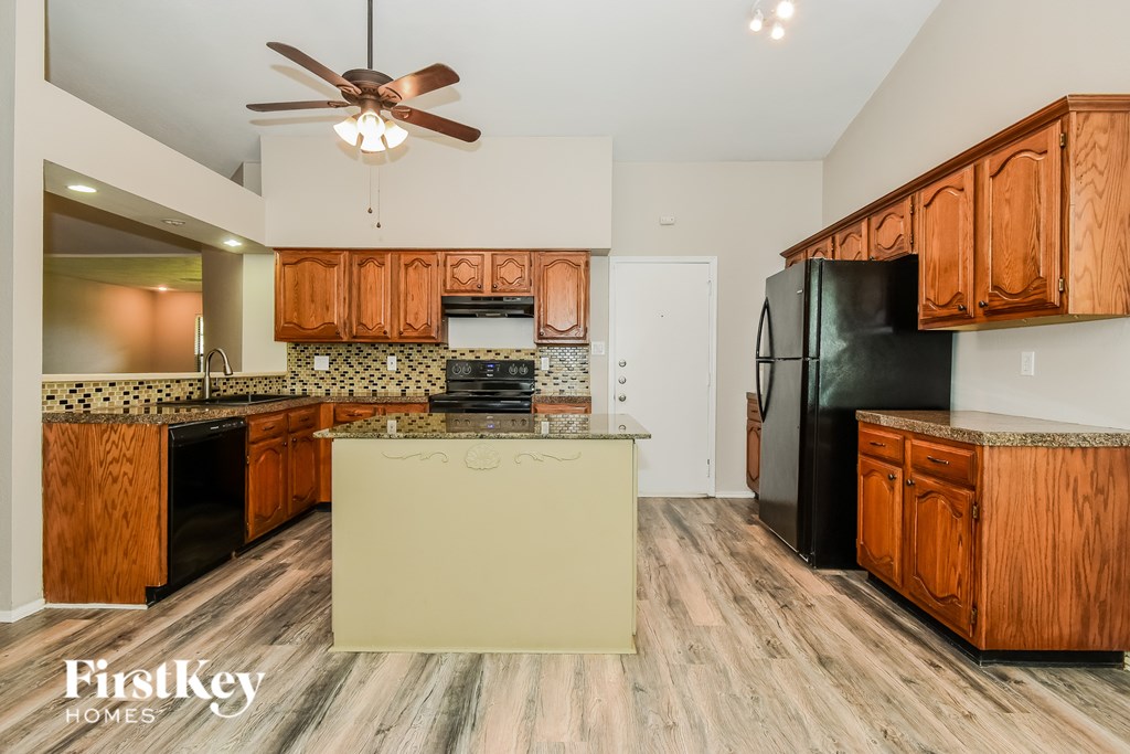 A kitchen with wooden cabinets and a black refrigerator.