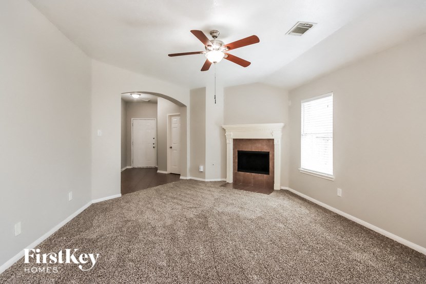 an empty living room with a ceiling fan and a fireplace
