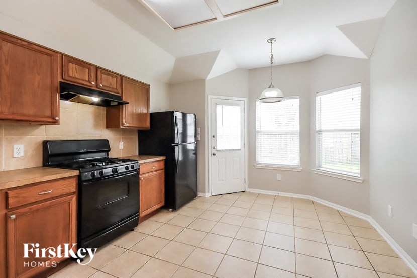 an empty kitchen with black appliances and wooden cabinets