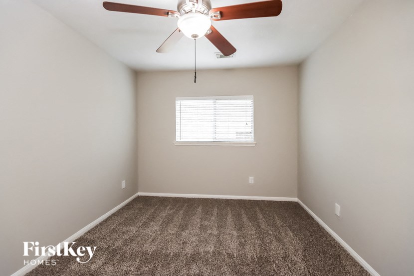 an empty room with a ceiling fan and a window