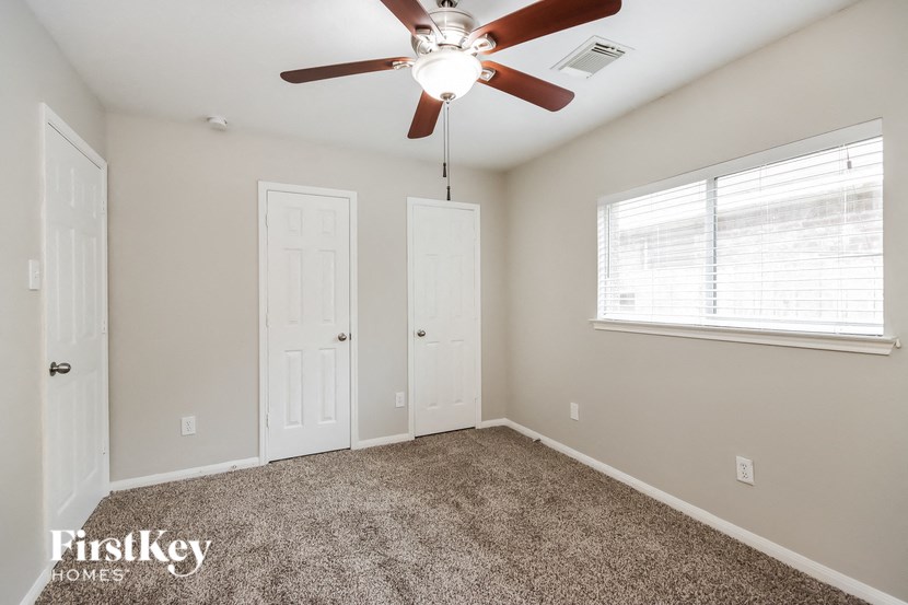 an empty bedroom with a ceiling fan and a closet