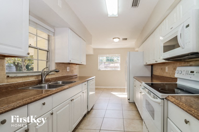 a kitchen with white cabinets and white appliances and a sink
