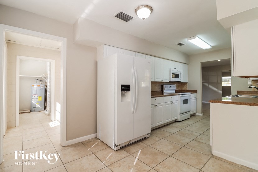 a large kitchen with white cabinets and a refrigerator