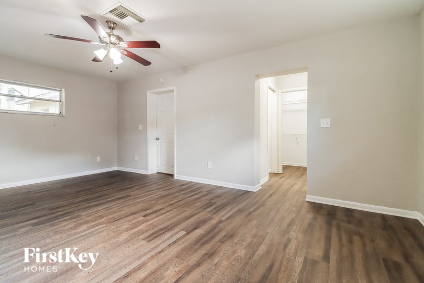 an empty living room with wood flooring and a ceiling fan