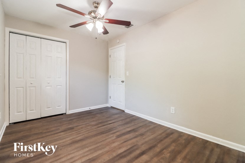 an empty living room with a ceiling fan and a closet