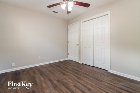 an empty bedroom with a ceiling fan and two closets