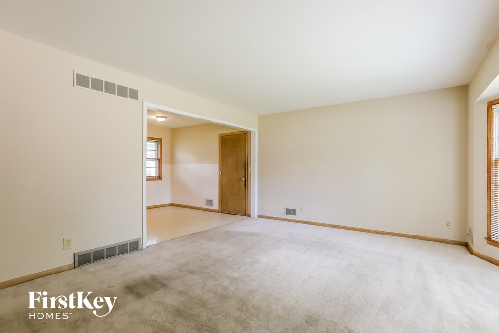 A spacious empty room with a doorway leading to another room.