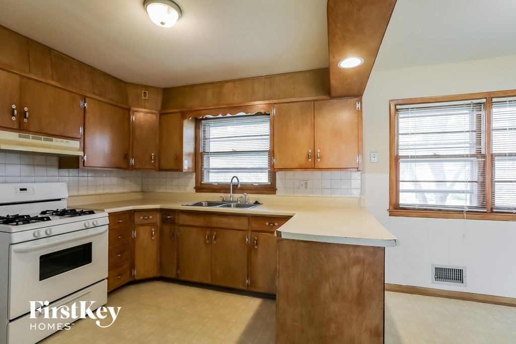 A kitchen with wooden cabinets and a white stove top oven.