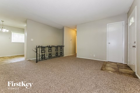 A spacious empty room with a carpeted floor and a metal staircase.