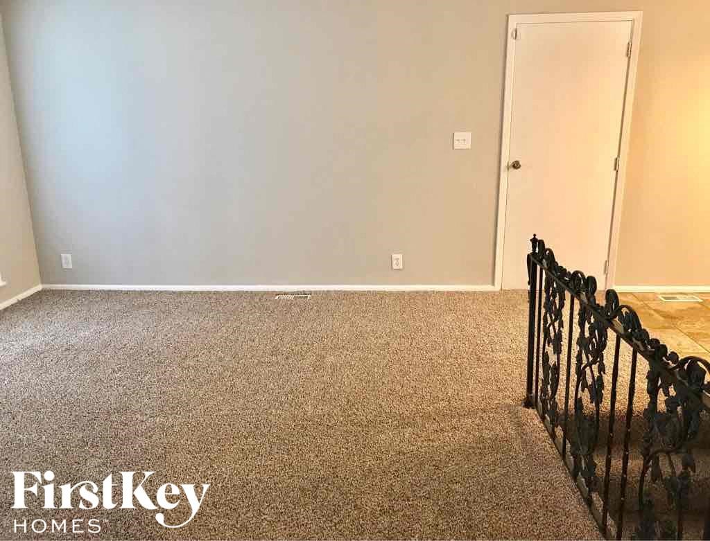 A room with a carpeted floor and a black metal fence.