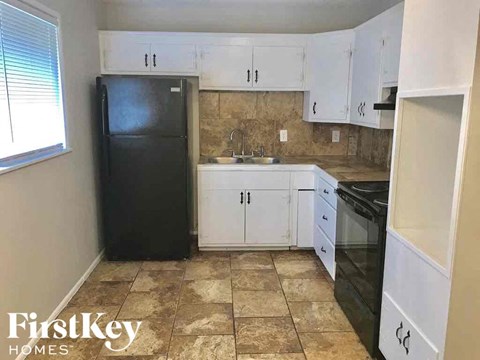 A kitchen with black appliances and white cabinets.
