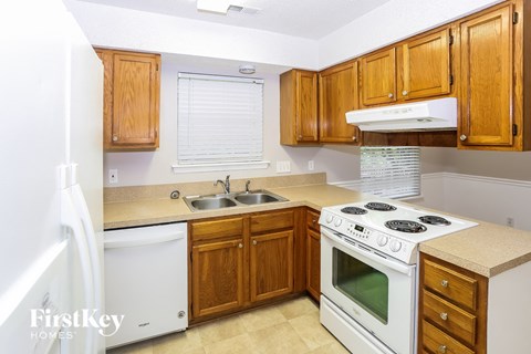 A kitchen with wooden cabinets and a white stove top oven.