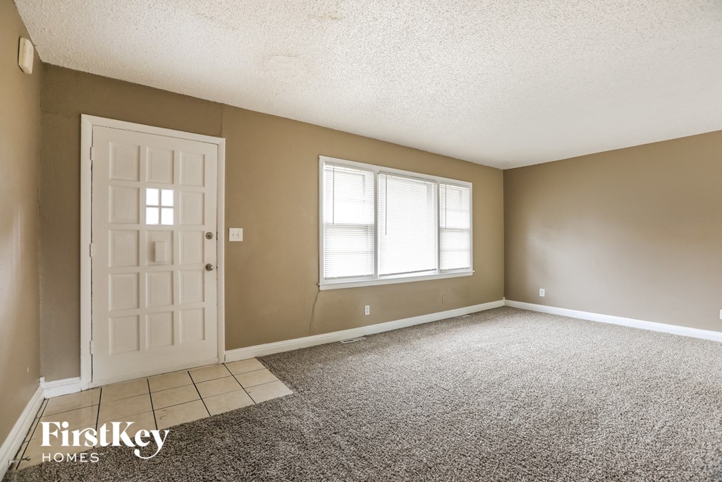 an empty living room with a white door and a window
