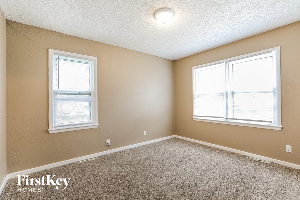 a bedroom with two windows and a carpeted floor