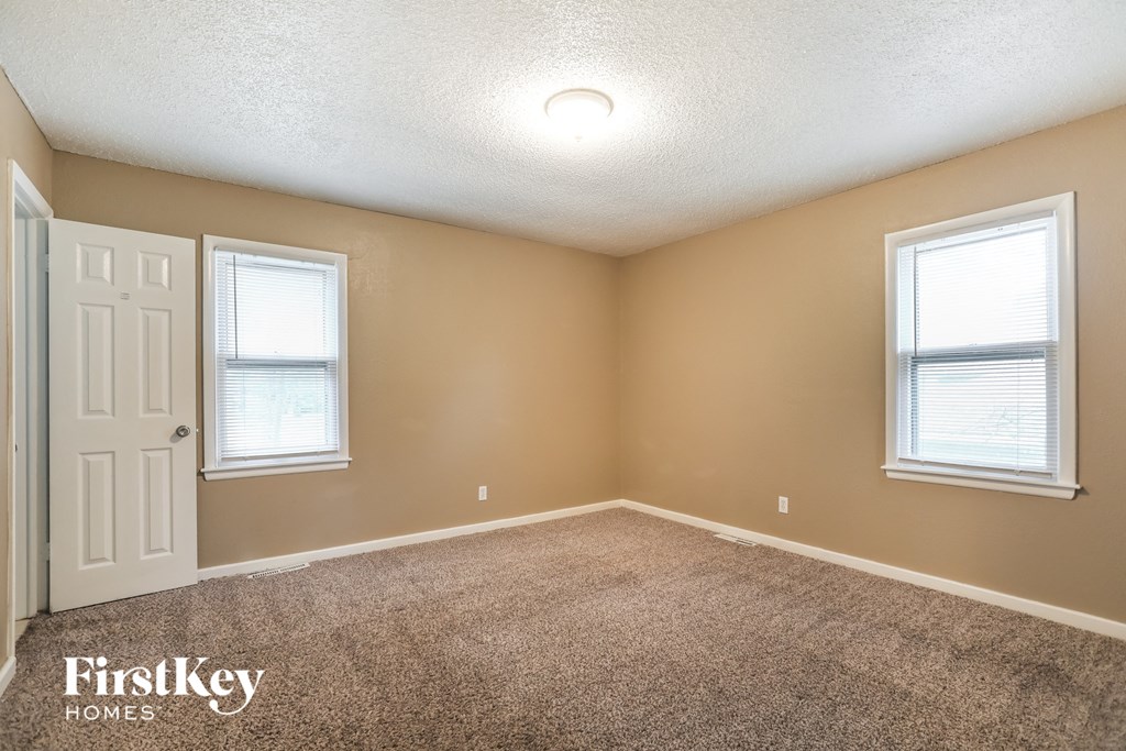 an empty room with two windows and a white door