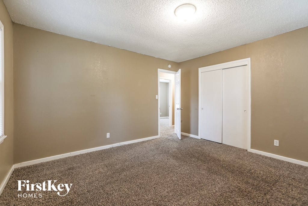 an empty living room with carpet and a door to a hallway