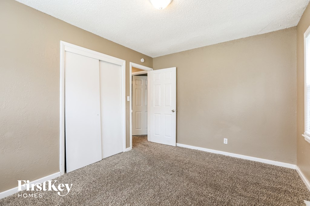 an empty living room with carpet and a door to a closet