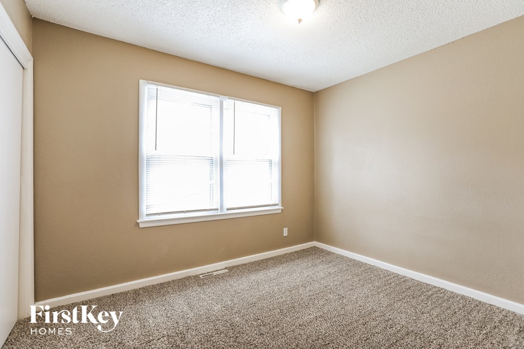 an empty room with a window and a carpeted floor