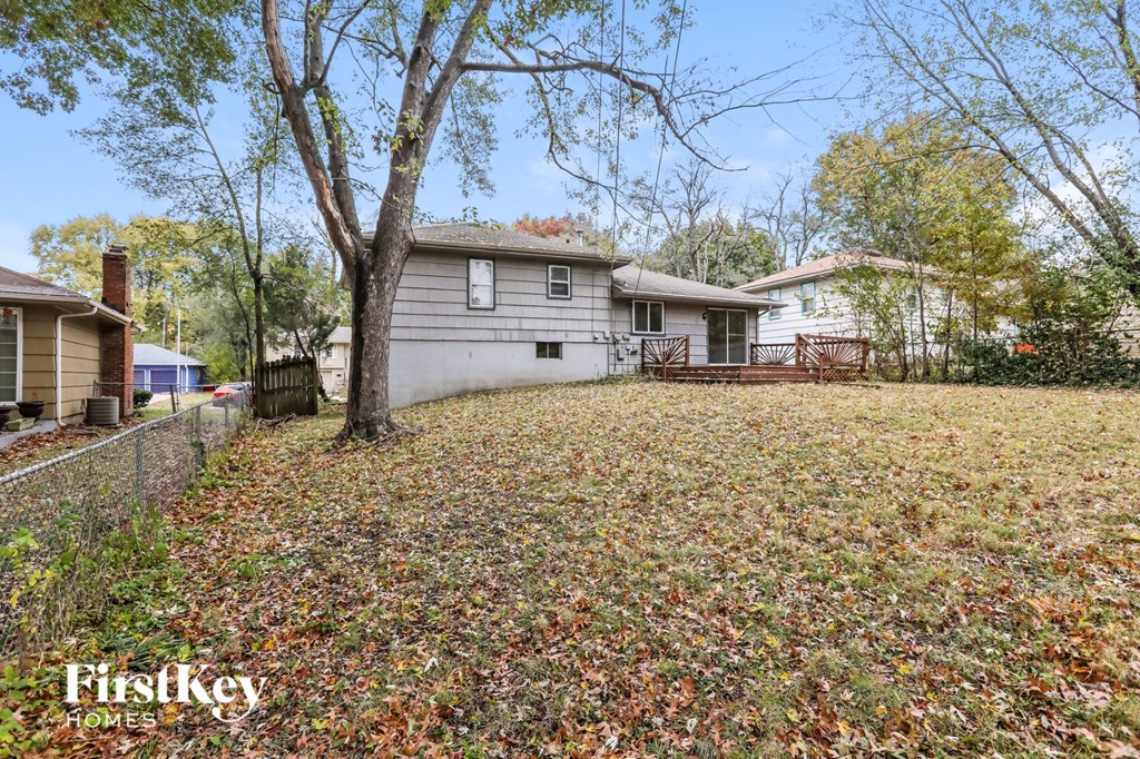 a backyard with a white house and a tree